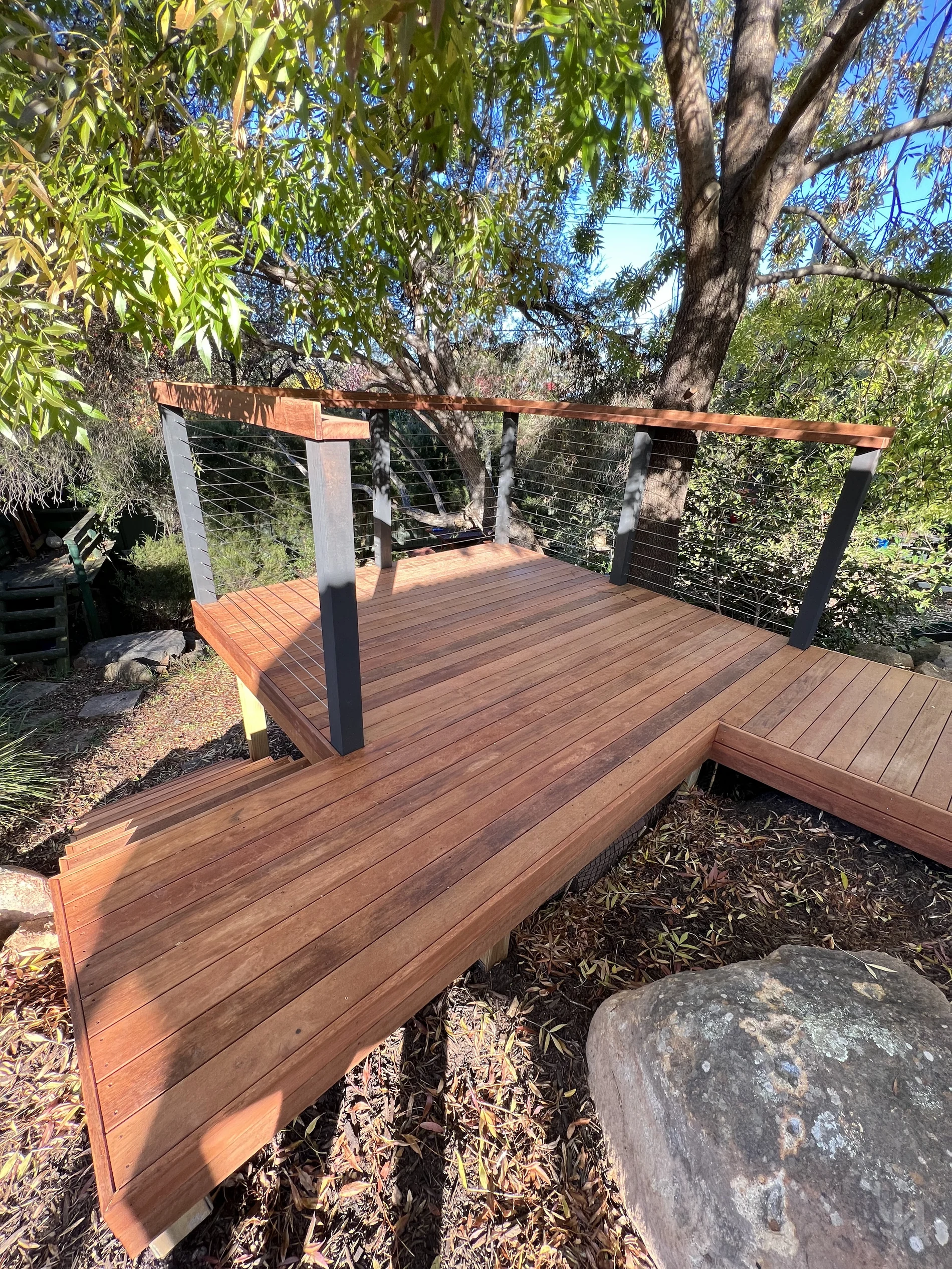 Merbau viewing platform deck with black posts and cable balustrade in a leafy ACT garden